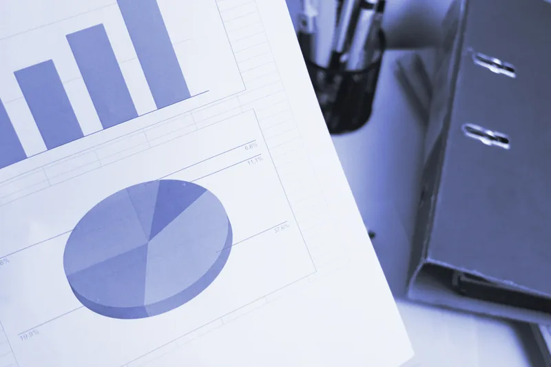 Informe impreso con gráficos de barras y de sectores junto a un archivador