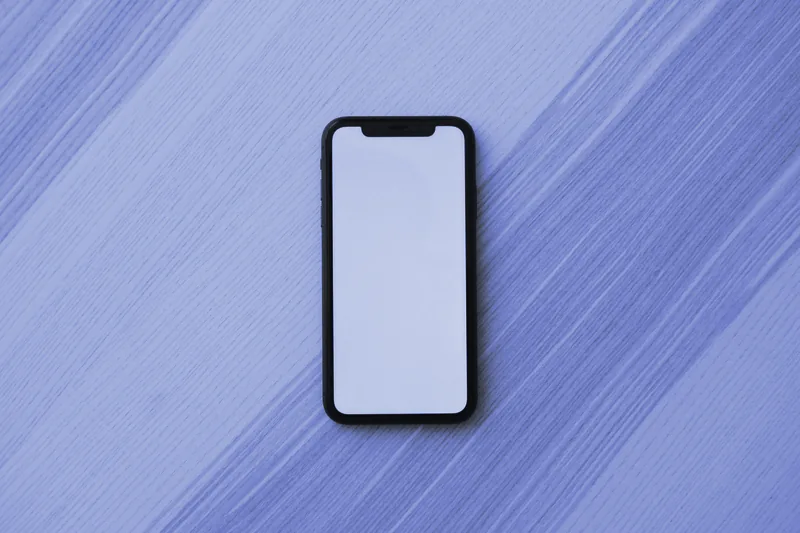 Móvil con la pantalla encendida sobre una mesa de madera clara