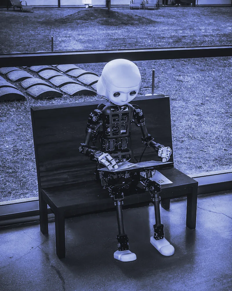 Robot humanoide sentado en un banco con una tableta en las manos