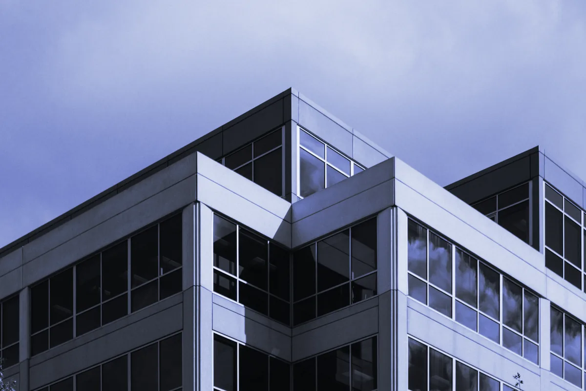 Esquina de un edificio de oficinas con ventanales bajo un cielo nublado