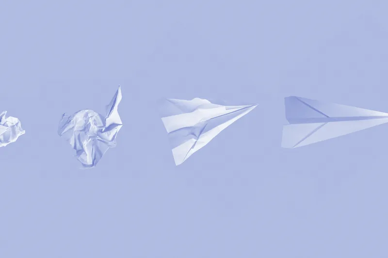 Bolas de papel arrugado que se convierten en aviones de papel sobre un fondo liso