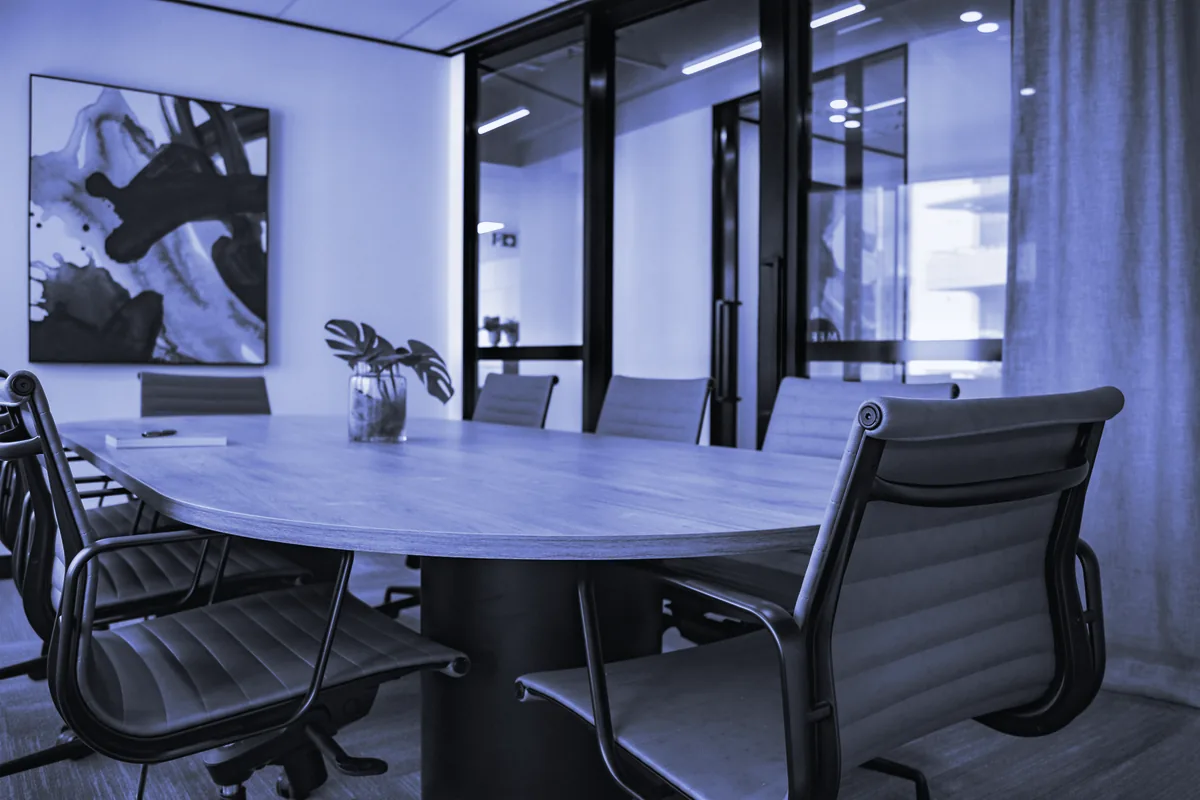 Sala de reuniones con mesa ovalada, sillas de oficina y un cuadro en la pared