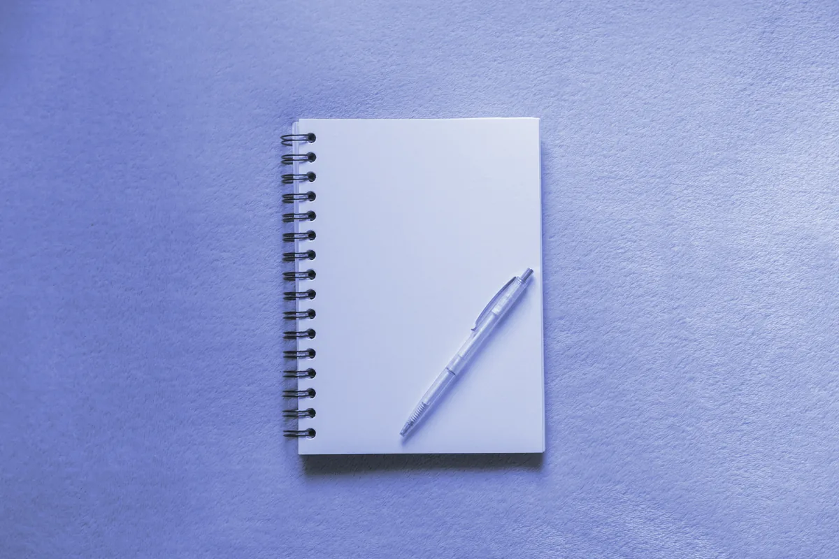 Cuaderno de espiral y bolígrafo sobre una mesa gris