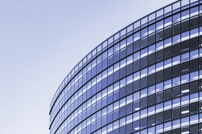 Fachada curva de cristal de un edificio de oficinas contra el cielo
