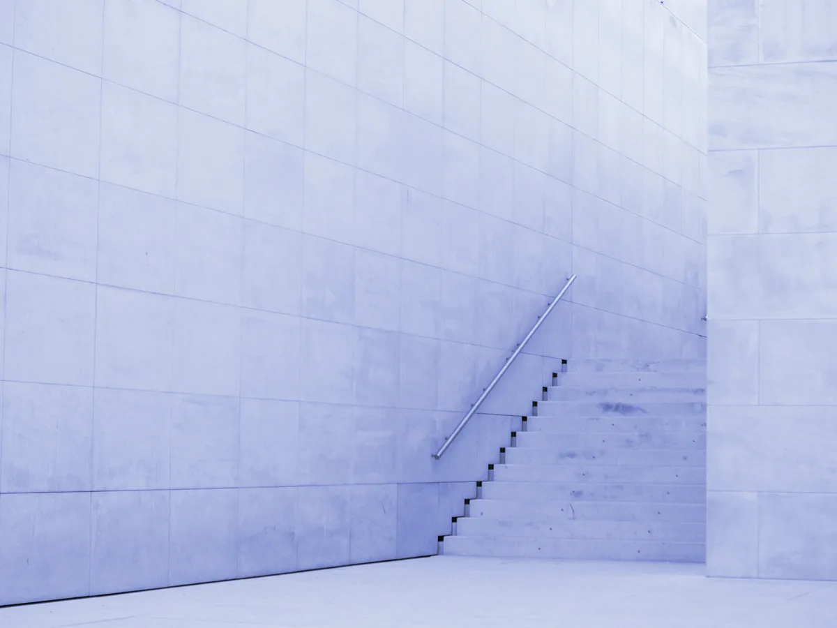 Escalera de hormigón blanco que sube junto a un muro
