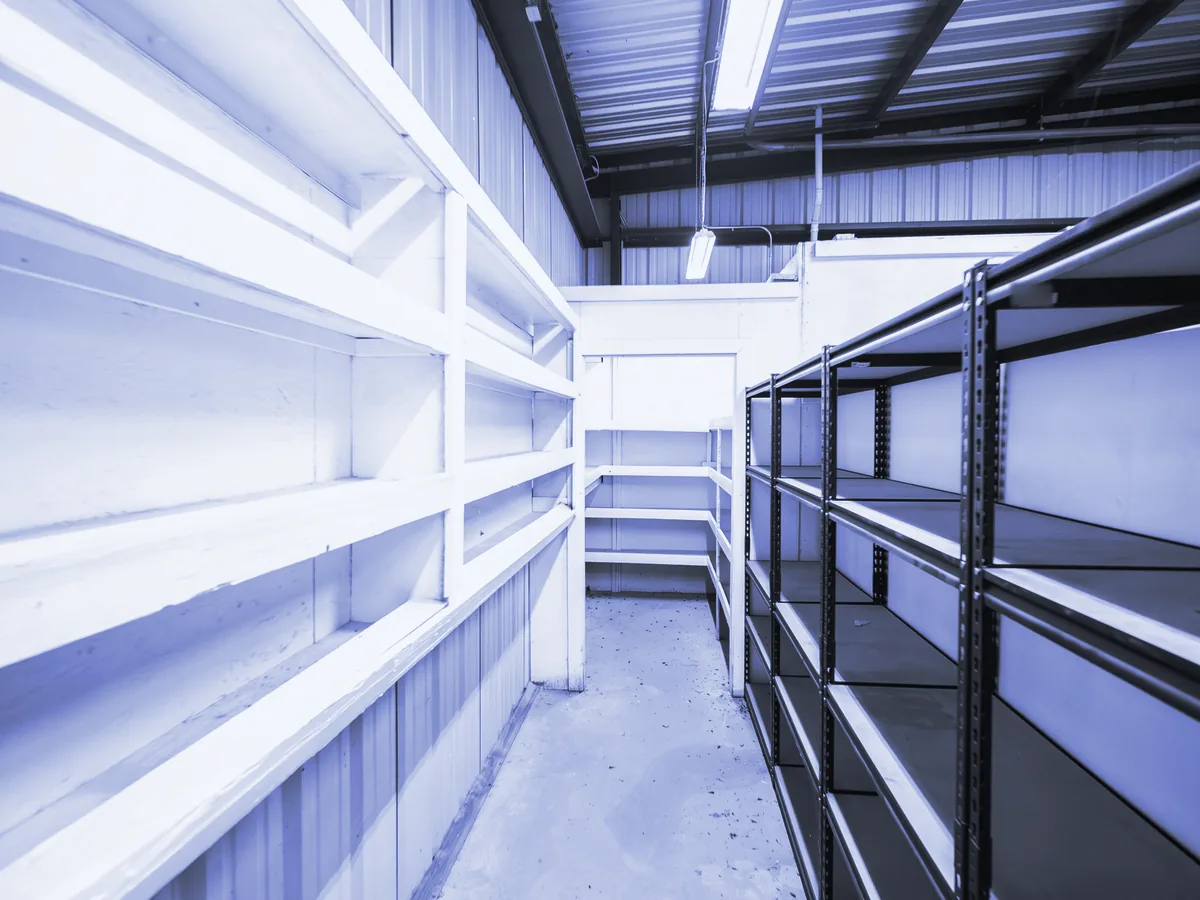 Almacén con estanterías vacías a ambos lados de un pasillo