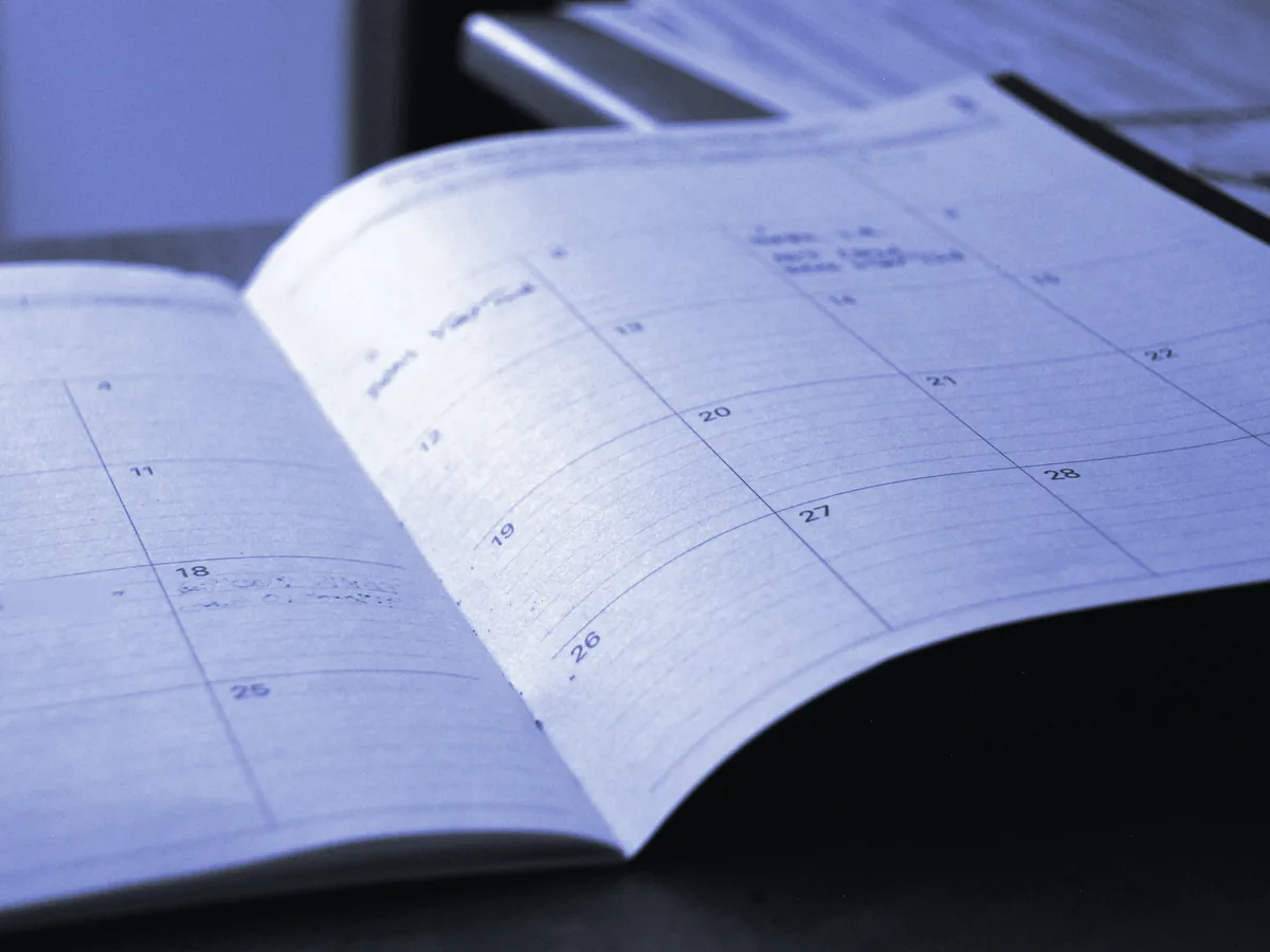 Agenda mensual abierta sobre una mesa, con los días del mes en cuadrícula
