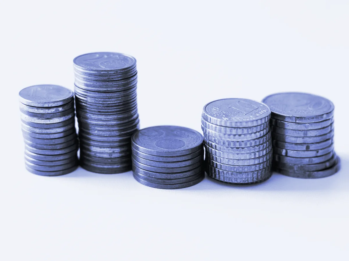 Pilas de monedas de céntimo de distinta altura sobre un fondo blanco